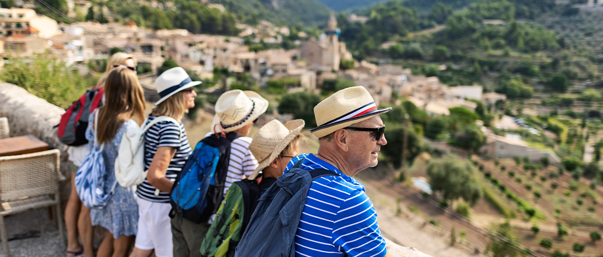 A family group looks out over medieval towns from an overlook on the Spanish island of Majorca.