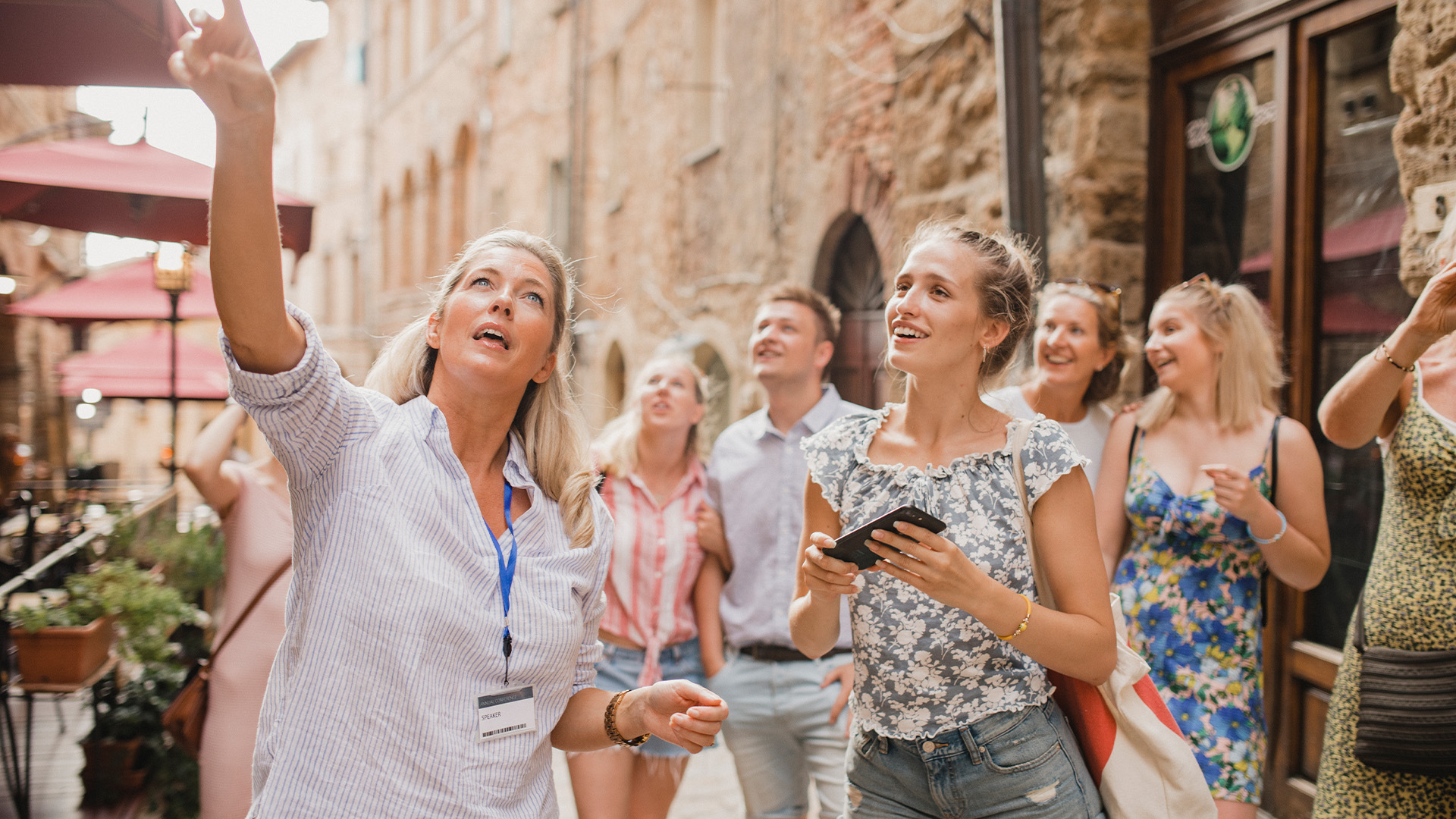 A tour guide leads a group of tourists through an Italian tour, pointing out landmarks.