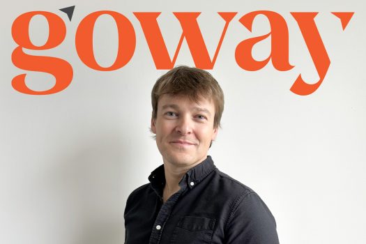 Sean Hebert, new VP, The Americas at Goway, poses in front of the logo.